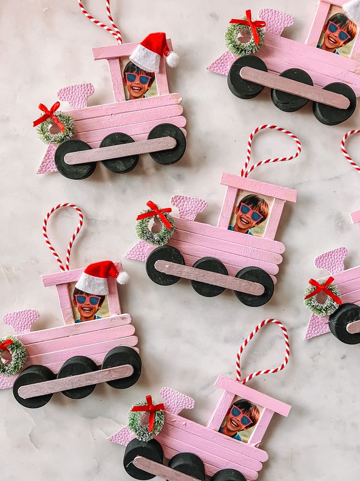 Pink train ornaments with holiday wreaths and kid's photo inserts on a white background.