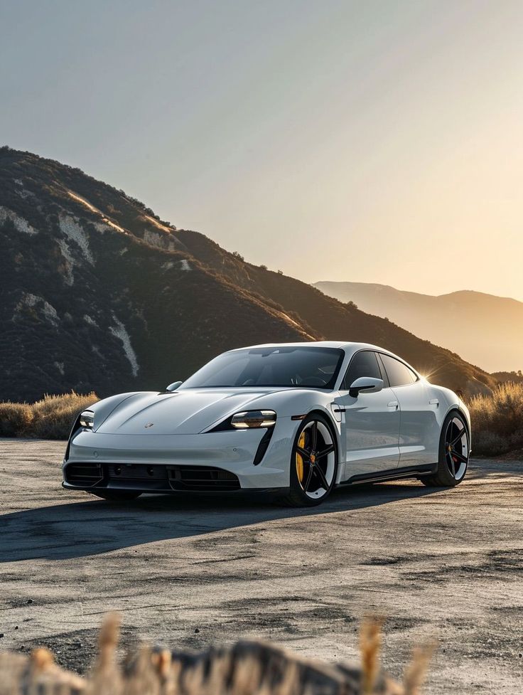 White sports car on a scenic mountain road at sunset, showcasing sleek design and modern luxury.