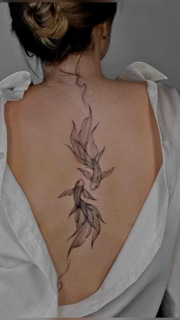 Intricate fish tattoo on woman's back in open white shirt. Detailed black ink art design.