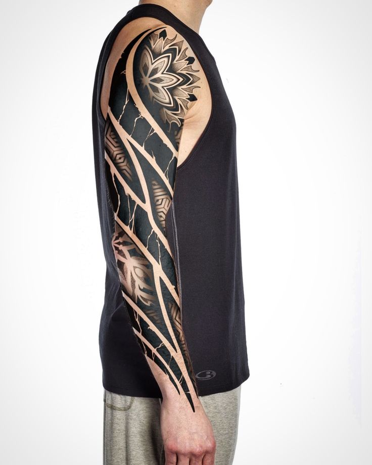 Man with intricate tribal sleeve tattoo and floral shoulder design wearing a sleeveless black shirt.