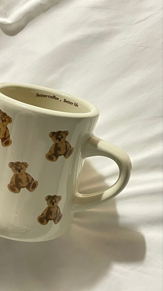 Teddy bear mug on white fabric background with Better coffee, Better life text inside. Cozy morning vibes.