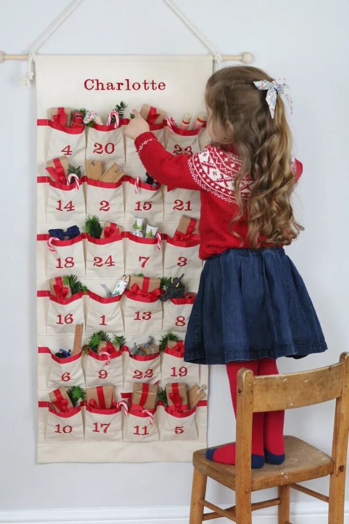 Girl in festive attire reaching into pocket calendar, adding Christmas decorations.