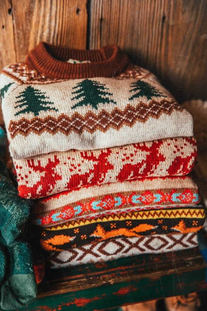 Stack of cozy, colorful knit sweaters with festive patterns, perfect for winter warmth and style.