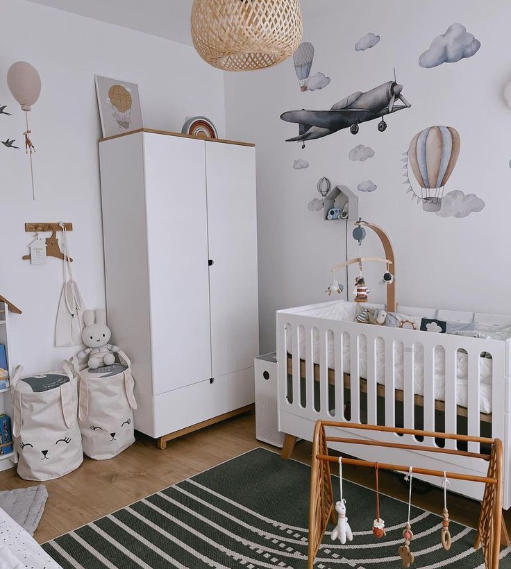 Modern nursery with crib, hot air balloon and airplane wall decals, cozy decor, and storage baskets.