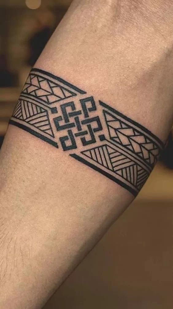 Geometric armband tattoo with intricate black line design on forearm.