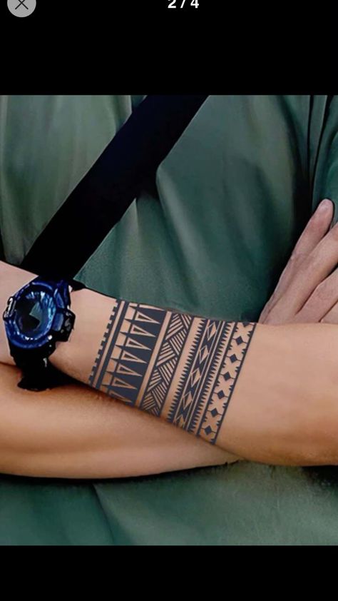 Arm with tribal tattoo and black watch, crossed and wearing a green shirt.