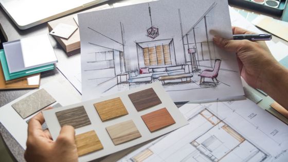 Architect’s hands holding interior design sketches and color palette samples for a modern living room layout.