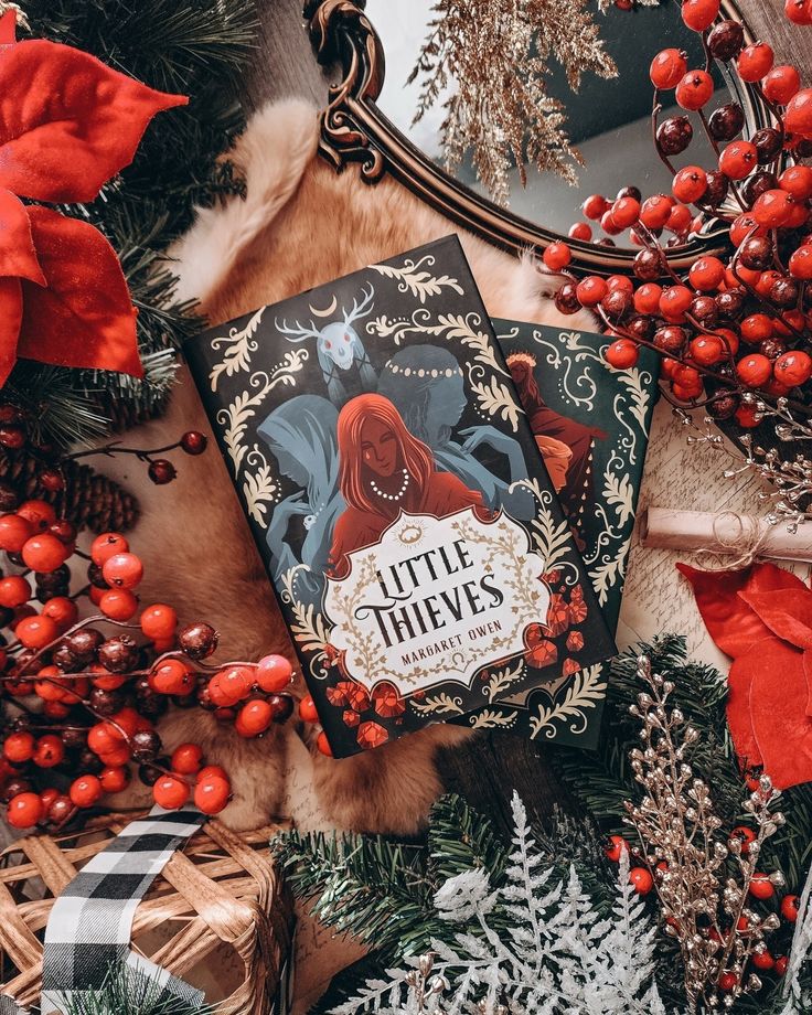 Little Thieves book on rustic holiday background with red berries and green foliage, festive and cozy setting.