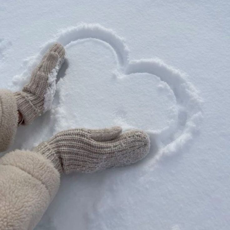 Gloved hands shaping a heart in the snow, symbolizing winter love and warmth.