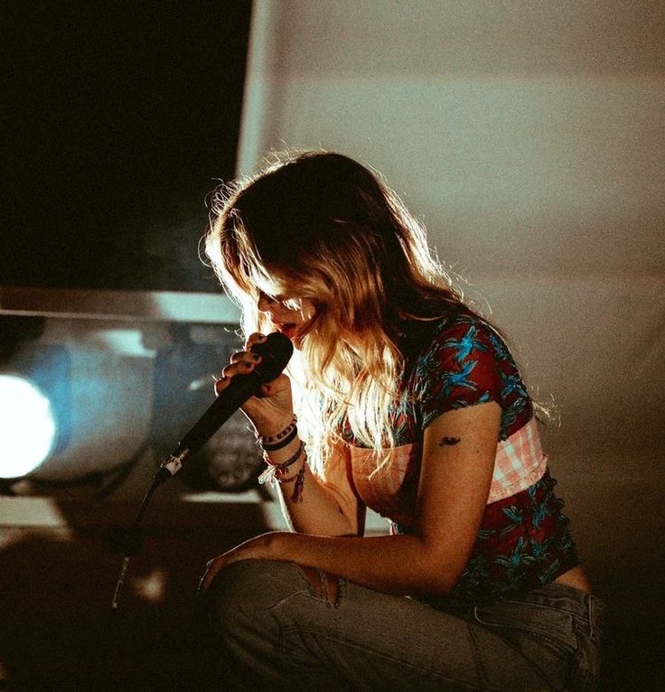 Singer performing on stage with microphone under dramatic lighting.