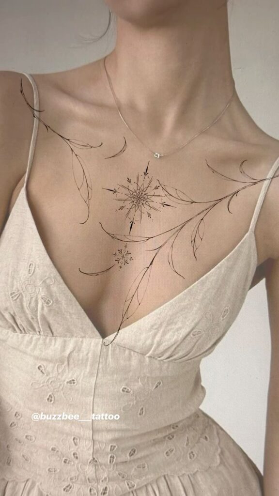 Elegant floral chest tattoo on woman in cream dress, fine line art.