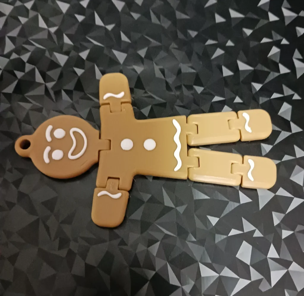 Toy gingerbread figure with movable limbs on geometric black background.