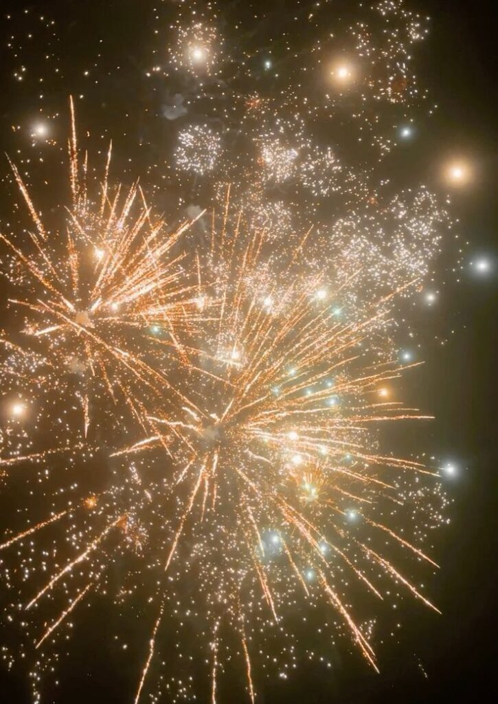 Bright golden fireworks exploding against a dark sky, illuminating the night with festive celebration and joy.