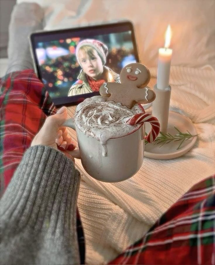 Cozy winter scene: hot chocolate with a gingerbread cookie, warm blanket, and a movie on a tablet.