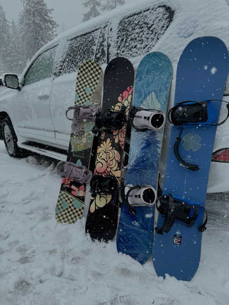 Snow-covered car with colorful snowboards leaning against it in a snowy landscape.