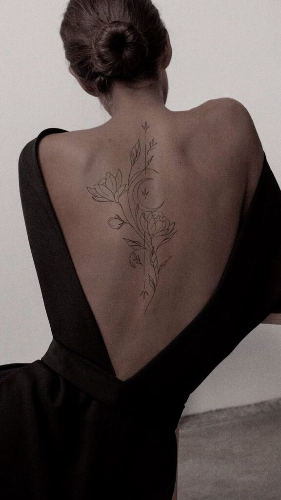 Woman with floral back tattoo wearing an elegant black dress, showcasing minimalist body art.