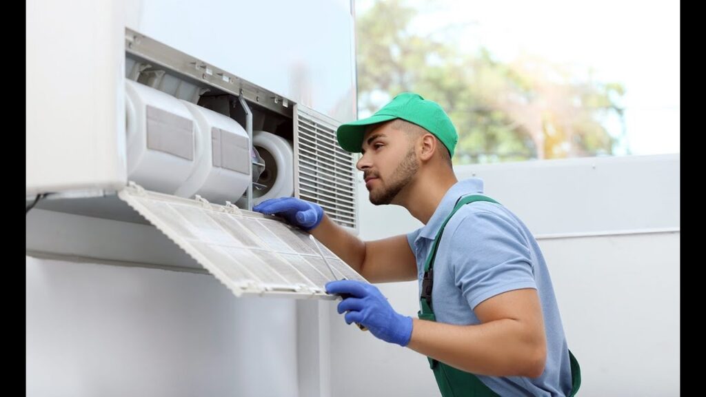 Technician servicing air conditioner unit for maintenance and repair.