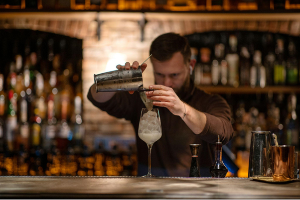 Bartender expertly crafting a cocktail in a dimly lit bar.