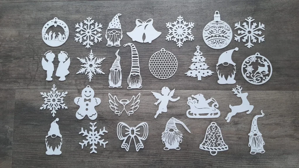 White Christmas-themed paper ornaments, including snowflakes, angels, and gnomes on a wooden background.