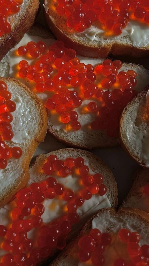 Slices of bread topped with red caviar and creamy spread, showcasing a gourmet snack close-up.