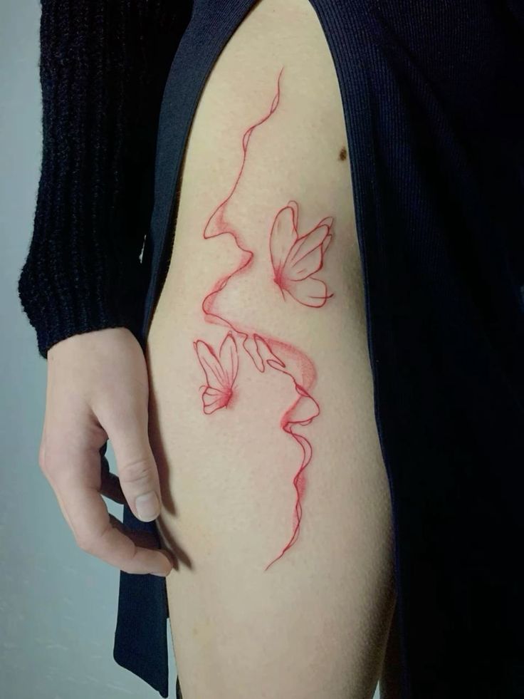 Minimalistic red butterfly tattoo design on a person's hip, featuring delicate linework and artistic detail.