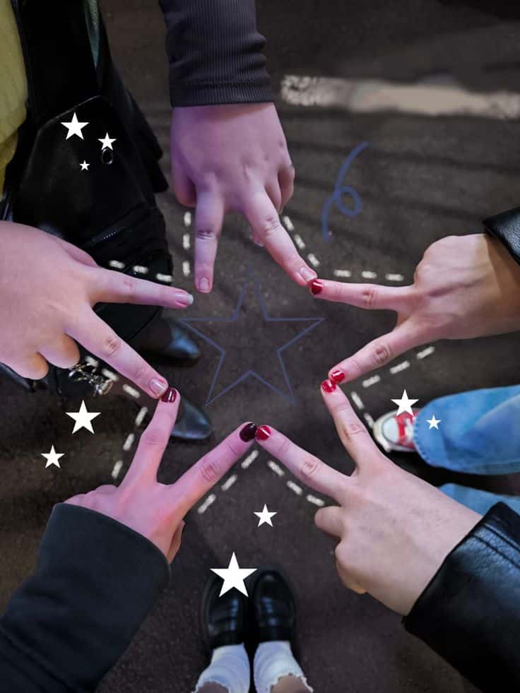 Five hands forming a star with painted nails, surrounded by stars, on a dark background. Creative friendship concept.