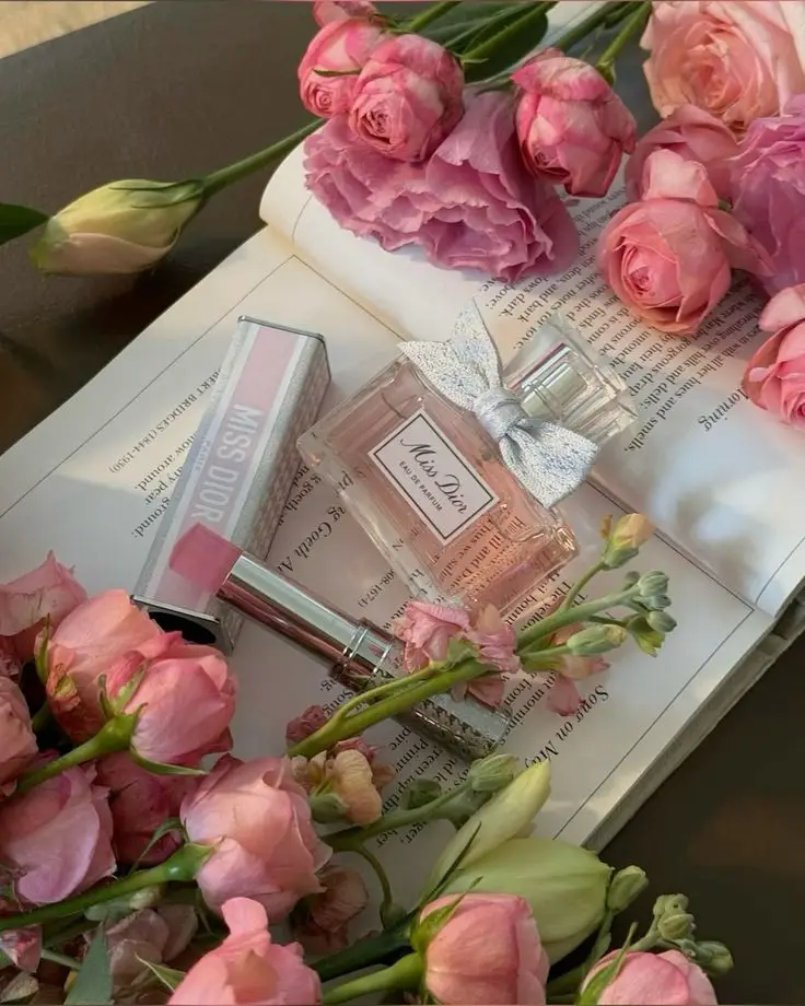 𝒟𝐼𝒪𝑅 🌷 Miss Dior perfume, pink lipstick, and flowers on open book create a romantic and elegant aesthetic. | Sky Rye Design Miss Dior perfume, pink lipstick, and flowers on open book create a romantic and elegant aesthetic.