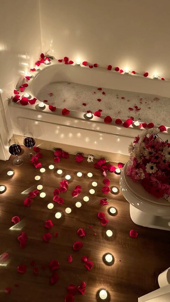 Romantic bath setup with rose petals, candles, and wine, ideal for relaxation and a cozy evening ambiance.