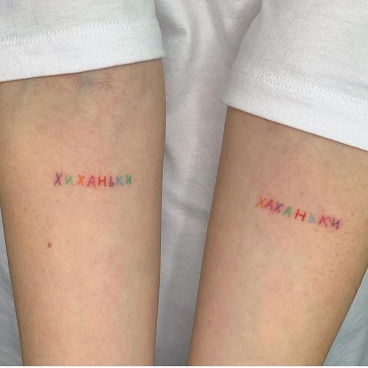 Colorful small text tattoos on inner arms with Cyrillic letters, displayed side by side on light skin.