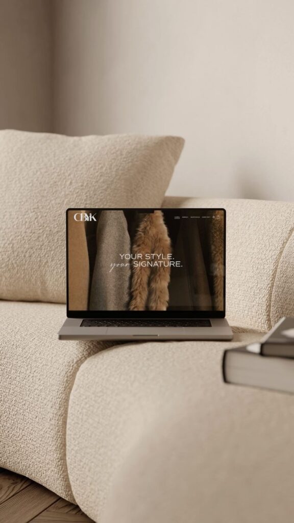 Laptop on a cozy beige couch displaying a fashion website with the text Your Style, Your Signature.