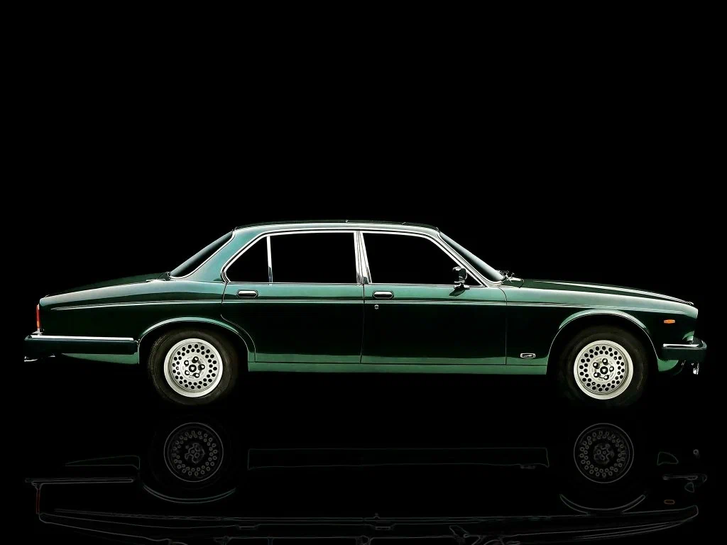 Classic green luxury car on black background, showcasing sleek design and timeless elegance.