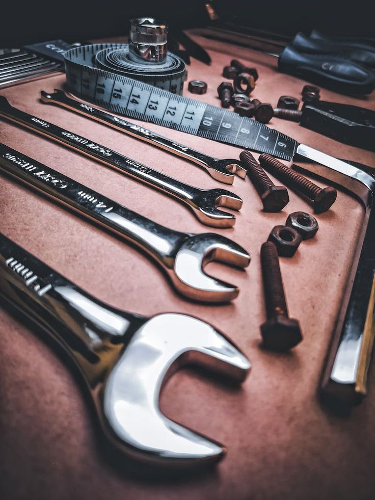 Close-up of wrenches, tape measure, bolts, and nuts arranged on a workbench.