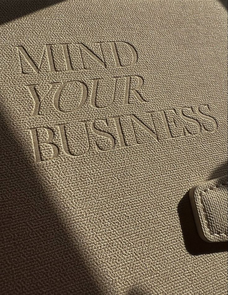 Textured fabric embossed with Mind Your Business in sunlight.