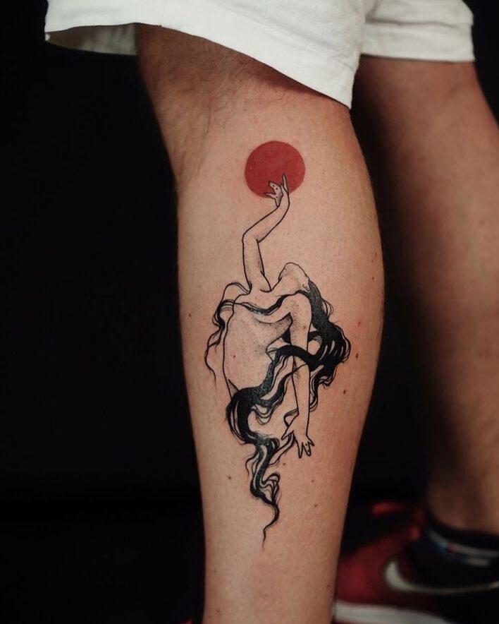 Tattoo of an abstract woman reaching towards a red circle, inked on a person's calf, detailed black and red design.