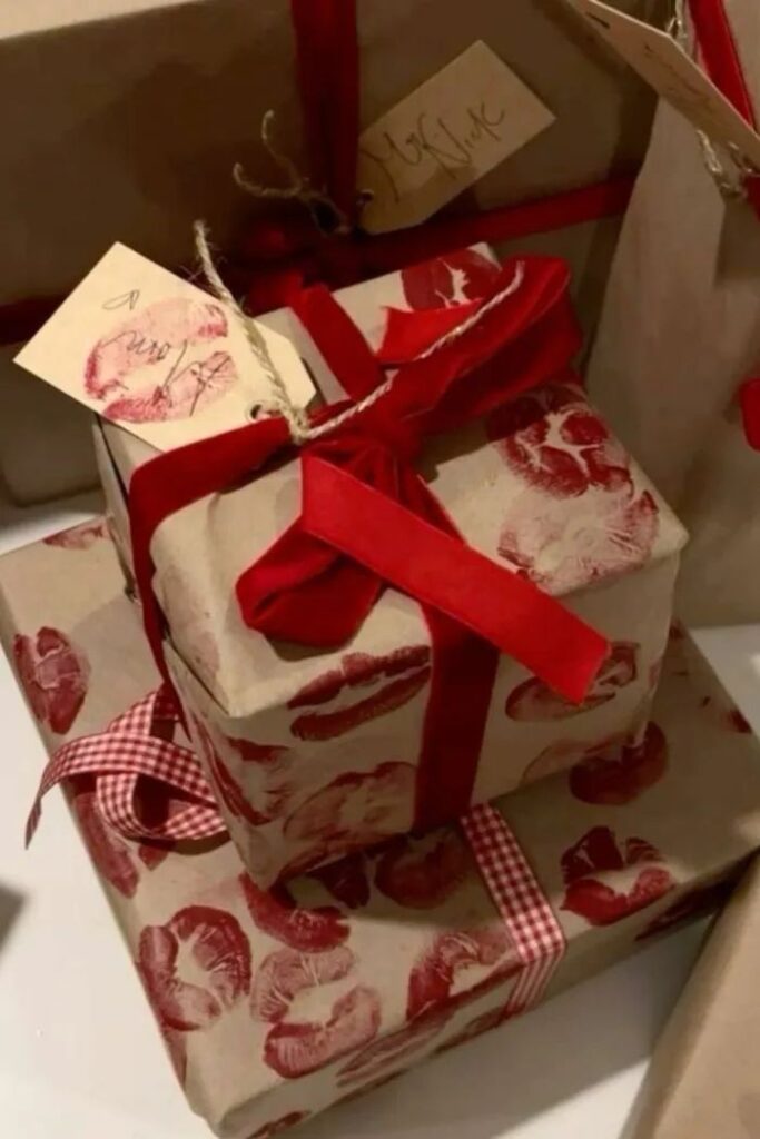 Beautifully wrapped gifts in paper with red lips pattern, adorned with red ribbons and gift tags.