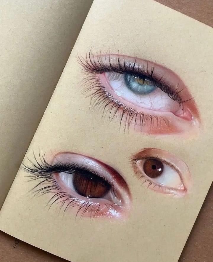 Realistic eye drawings on sketchbook pages, showcasing vibrant blue and brown eyes in close-up detail.