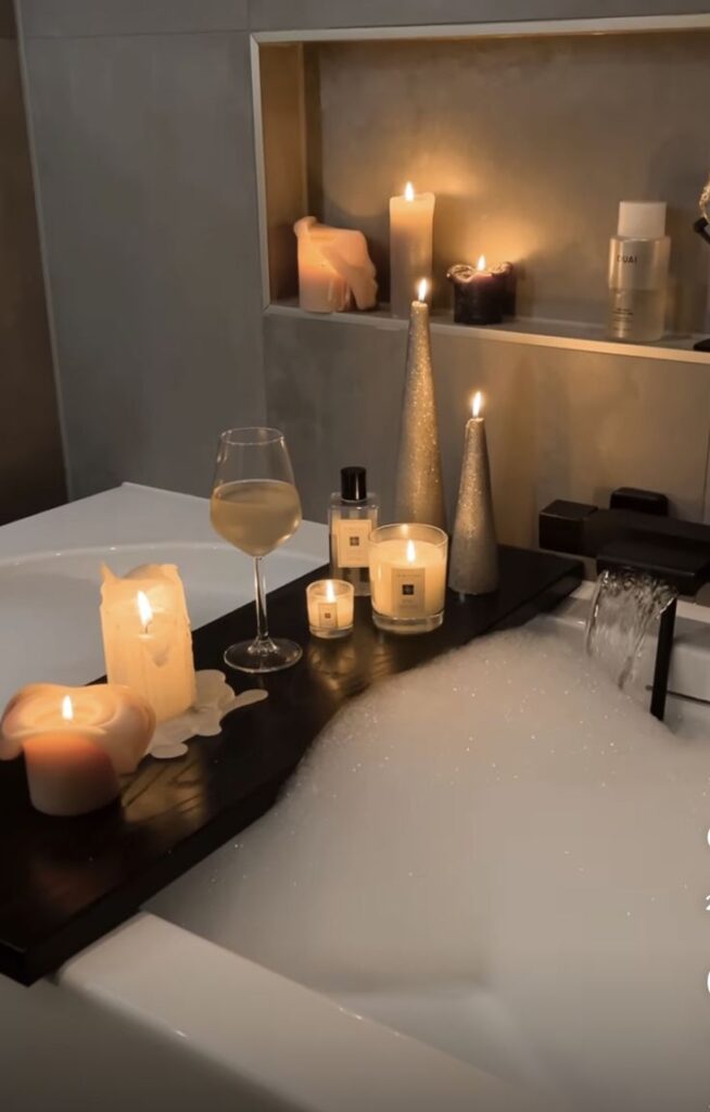 Relaxing bubble bath with candles, wine, and luxury products for a soothing spa-like experience at home.