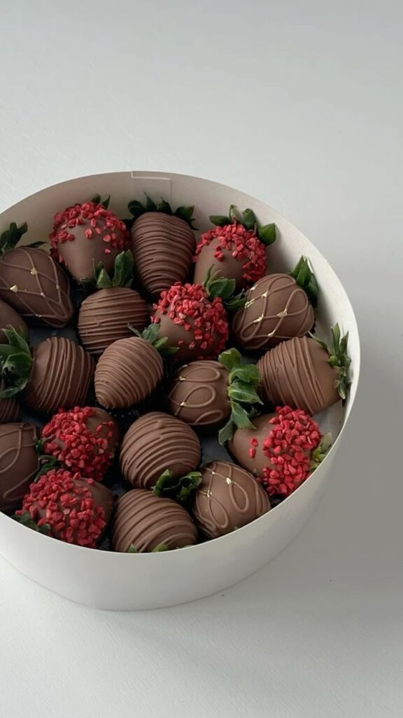 Box of gourmet chocolate-covered strawberries with red sprinkles, elegantly presented, perfect for gifting.