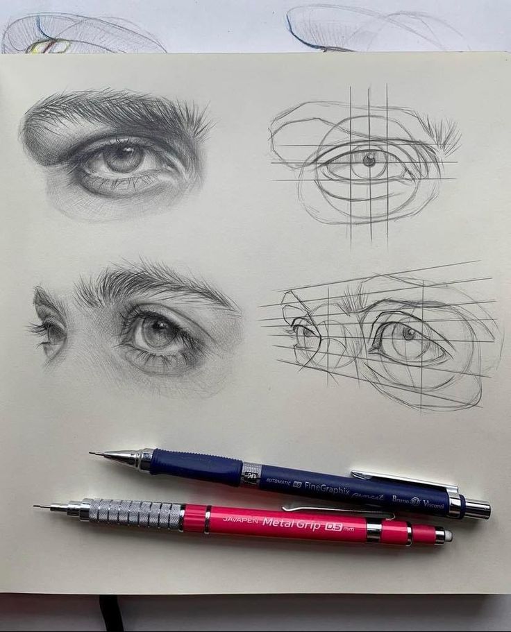 Pencil sketches of realistic eyes with grid guidelines, featuring two mechanical pencils on the paper.