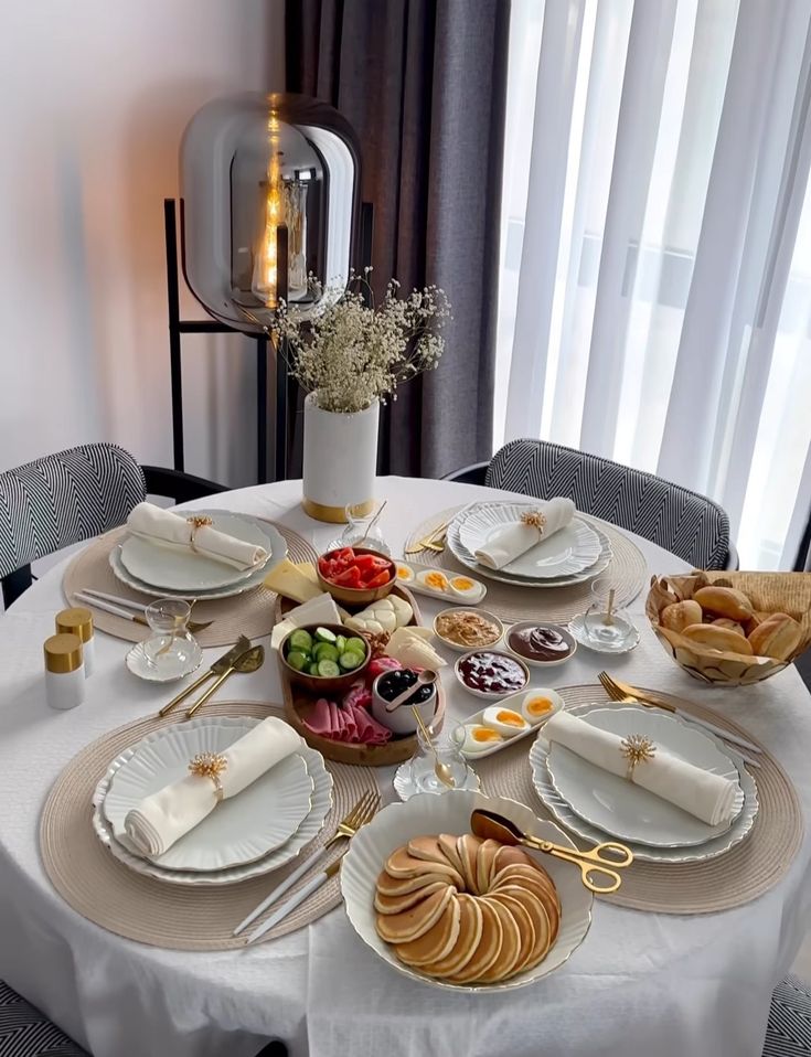 Elegant breakfast table with pancakes, fresh vegetables, cheese, and bread, set with modern decor and soft lighting.