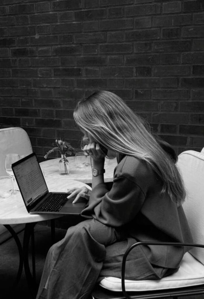 Woman working on a laptop at a cafe, focused and engaged in a peaceful atmosphere.