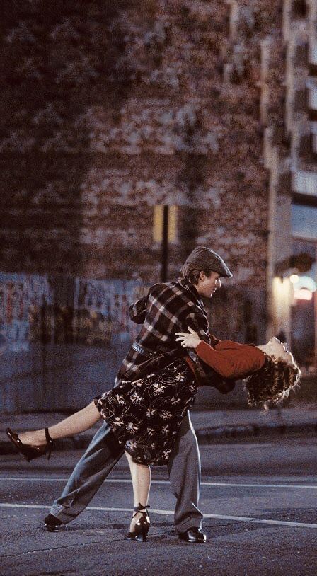 Couple dancing passionately under city lights at night.