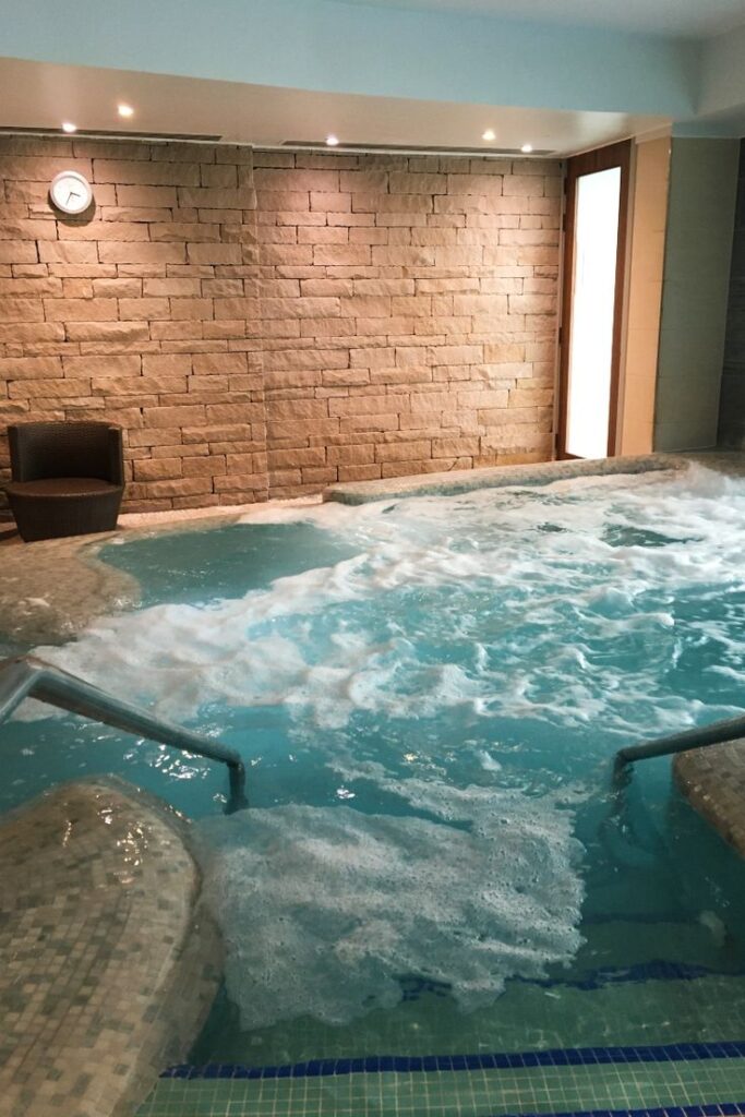 Indoor spa hot tub with bubbling water, stone wall background, and relaxing ambiance.