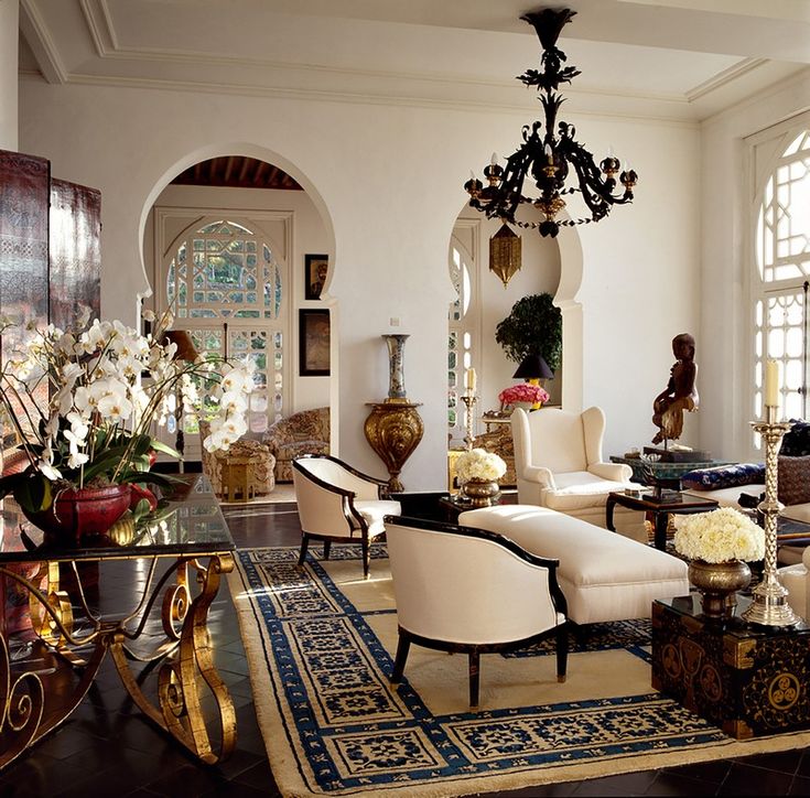 Elegant living room with ornate furniture, chandelier, archways, and floral decor in a luxurious setting.