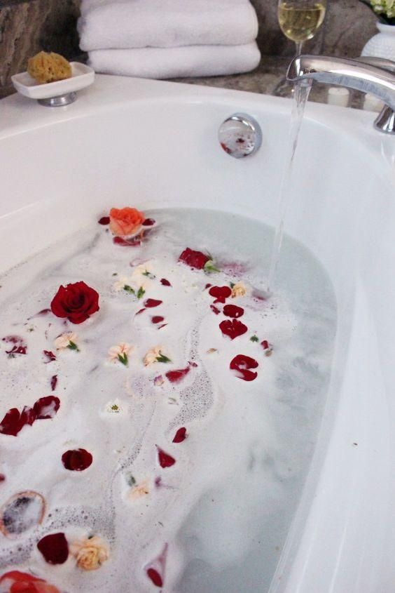 Luxurious bath with rose petals, fluffy towels, and a glass of wine for ultimate relaxation.