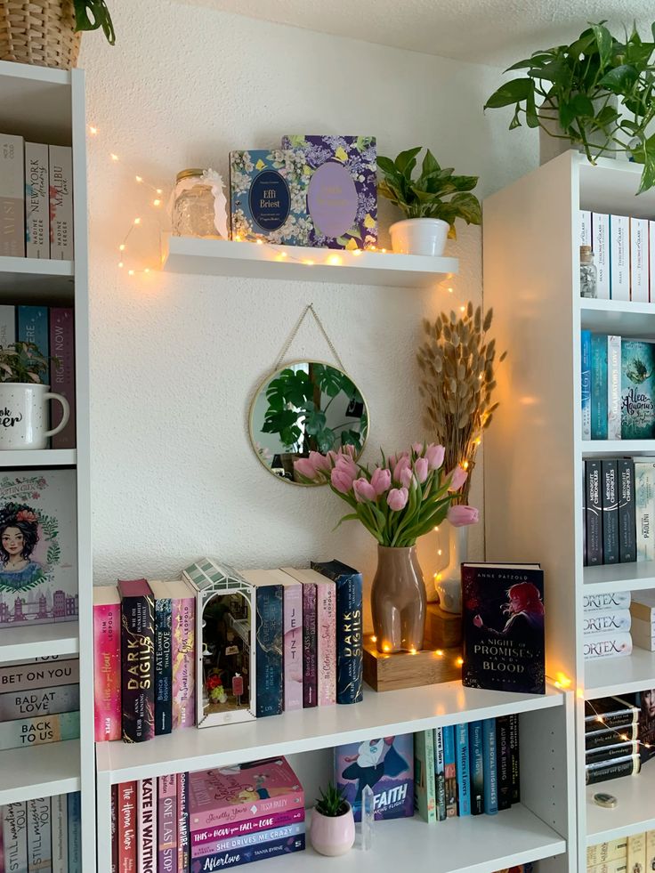 Cozy bookshelf with colorful books, string lights, tulips in a vase, and plants creating an inviting reading nook.