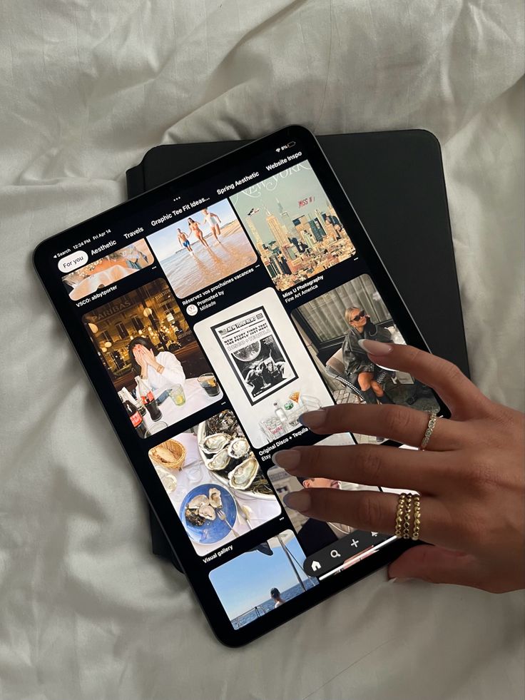 Tablet displaying Pinterest interface with aesthetic images; hand with rings interacting with the screen.