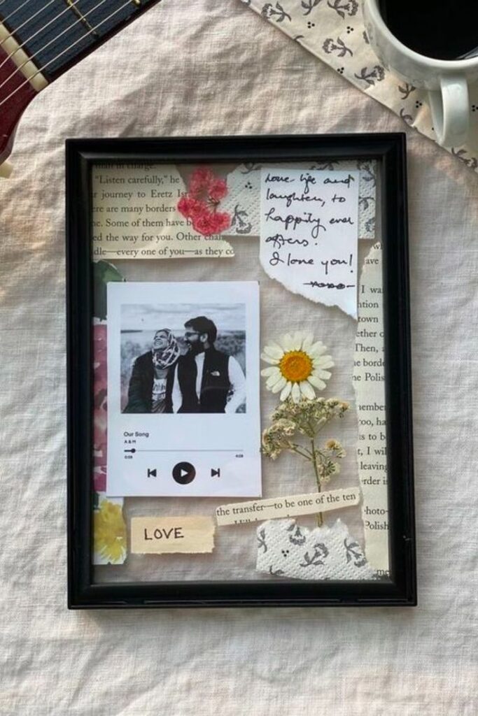 Framed collage with dried flowers, a romantic note, and a black-and-white couple's photo on a music-themed background.