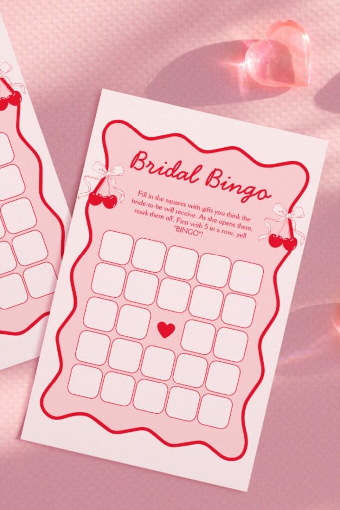 Bridal bingo card with decorative red border, heart symbol, and gift guessing instructions on a pink background.