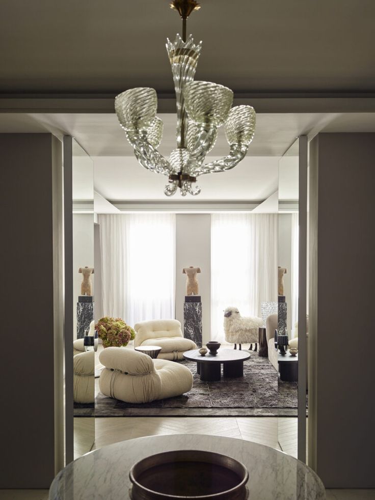 Luxurious living room with modern furniture, elegant chandelier, and decorative sculptures.